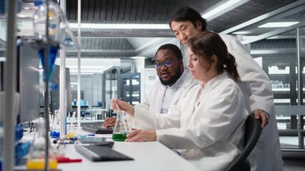 Multiracial researchers in lab inspecting liquids in test tube, looking for breakthroughs during clinical trials. Multiethnic employees comparing chemicals vials, testing right formula, camera A