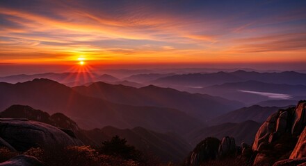 Majestic mountain landscape with colorful sunrise over misty peaks, dramatic sky and scenic layers