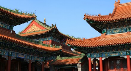 Naklejka premium Traditional Chinese architecture with ornate roofs and vibrant red, green, and gold detailing under blue sky
