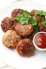 Delicious patties with parsley and ketchup on white wooden table, closeup