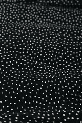 Black fabric with white polka dot pattern, classic textile texture.