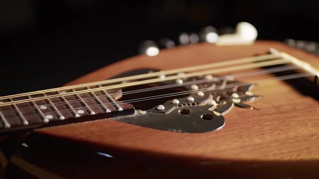 Close-up shots of a mandolin instrument with strings and wooden structure in a dark studio