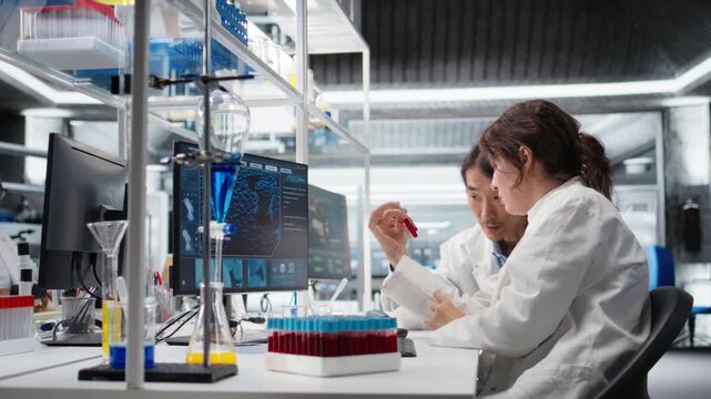 Multiethnic team of clinical laboratory technologists reviewing blood data during diagnostics study. Diverse coworkers validating sanguine fluids sample results, camera A