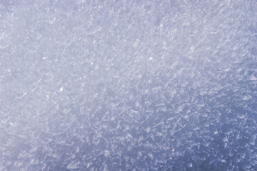 Snowy surface glistens under sunlight, revealing intricate textures and patterns in the frost-kissed landscape of winter