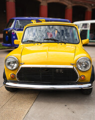 Vintage Yellow Compact Car – Retro Street Scene
Front view of a vintage yellow compact car parked outdoors beside other classic vehicles, evoking nostalgia and timeless design.