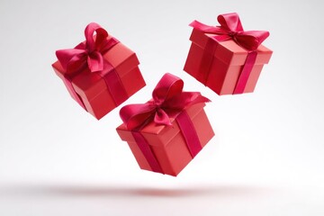 Three vibrant red gift boxes with satin bows suspended in mid air against a clean white background