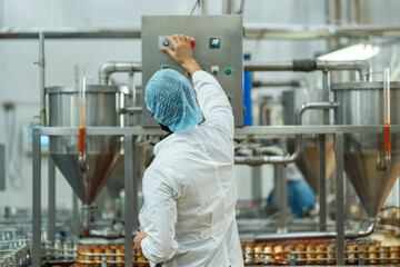 Inspector checking automated machinery in food production facility Focus on quality control safety and workflow efficiency. Worker overseeing food packaging machinery in a modern manufacturing plant.