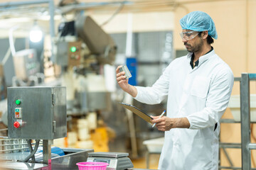 Inspector checking automated machinery in food production facility Focus on quality control safety and workflow efficiency. Worker overseeing food packaging machinery in a modern manufacturing plant.