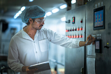 Professional worker analyzing operational data on production equipment in a state-of-the-art food...