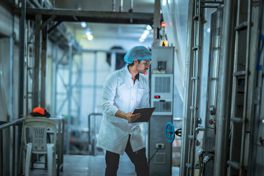 Professional worker analyzing operational data on production equipment in a state-of-the-art food factory Prioritizing efficiency and safety compliance.