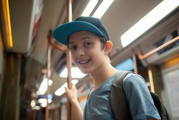smiling 12 year old boy with backpack in train carriage, subway, metro	