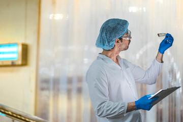 A Quality Assurance QA specialist in PPE audits a smart factory. He monitors the food safety and...