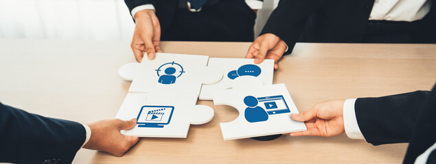 A group of professionals engaged in a collaborative marketing strategy session, using puzzle pieces...
