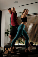 Couple engaged in a fitness routine in a modern home gym during the evening, focusing on balance...