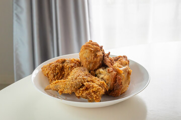 Crispy fried chicken in white plate on wood table