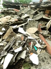 Close-up photo of building debris with broken concrete, bricks, and roof tiles after demolition....