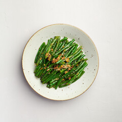 Asian style green beans with sesame and garlic on plate, top view