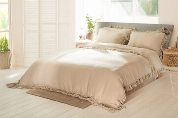 Minimalist cozy bedroom with a double bed. Double empty bed with beige pillows with texture for the...