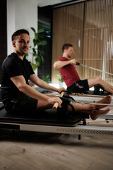 Fitness enthusiasts practicing pilates in a modern studio with equipment focusing on strength and...