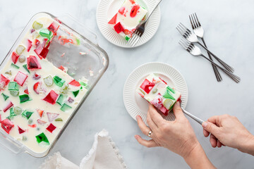 Top down view of hands serving a square of homemade gelatin dessert.