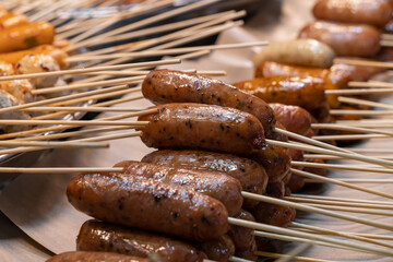 Close-up view of the stacked grilled sausages on skewers at market stall for sale.