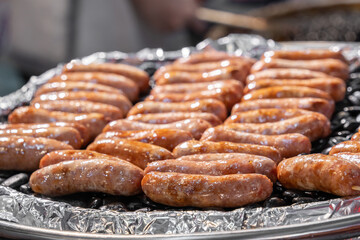 Close-up view of sizzling grilled sausages on foil tray