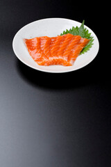 皿に盛られたサーモンのお刺身 黒背景