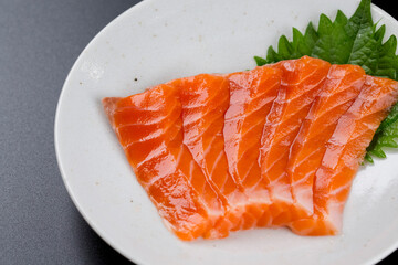 皿に盛られたサーモンのお刺身 黒背景