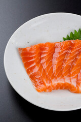 皿に盛られたサーモンのお刺身 黒背景