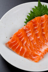 皿に盛られたサーモンのお刺身 黒背景