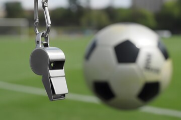 Soccer ball and referee whistle on a field