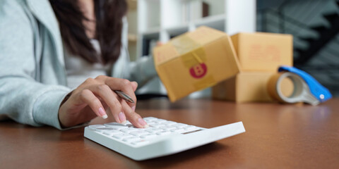 E-commerce: Woman calculating shipping costs while handling packages