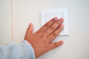 Child turns off the light switch in a cozy room