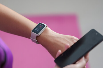 Fitness Tracker. Woman checking heart rate on smartwatch while holding smartphone.