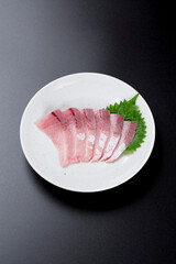 皿に盛られたブリのお刺身 黒背景
