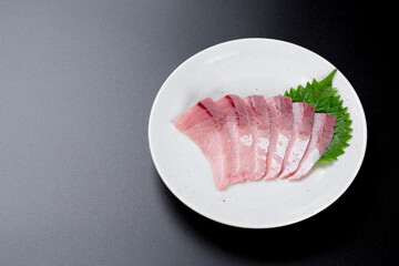 皿に盛られたブリのお刺身 黒背景