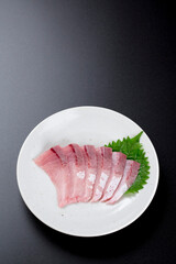 皿に盛られたブリのお刺身 黒背景