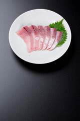 皿に盛られたブリのお刺身 黒背景