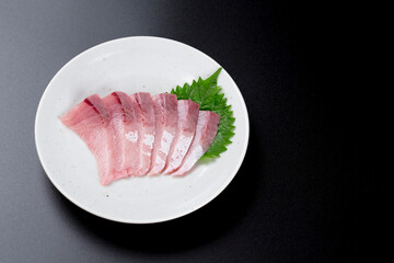 皿に盛られたブリのお刺身 黒背景