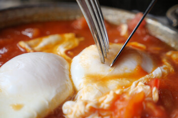 Cooking poached eggs in tomato sauce on a stove