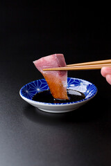 皿に盛られたブリのお刺身 黒背景