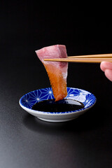 皿に盛られたブリのお刺身 黒背景