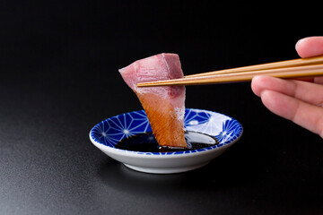 皿に盛られたブリのお刺身 黒背景