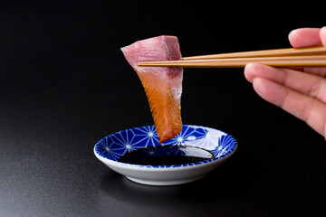 皿に盛られたブリのお刺身 黒背景