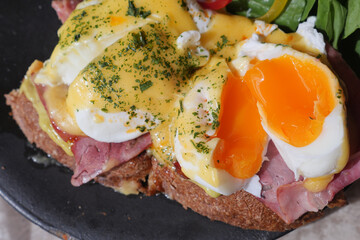 Delicious eggs benedict with spinach and ham on a toast 