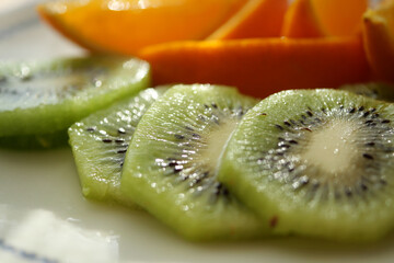 Fresh kiwi and orange slices arranged on a plate