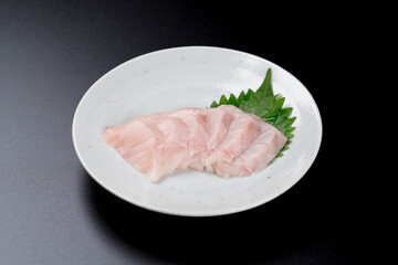 皿に盛られたサワラのお刺身 黒背景