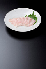 皿に盛られたサワラのお刺身 黒背景