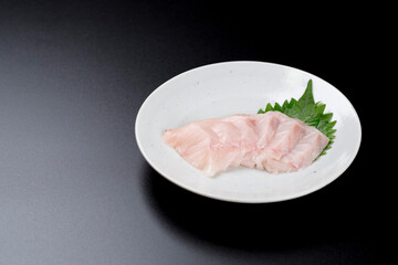 皿に盛られたサワラのお刺身 黒背景