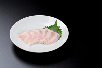 皿に盛られたサワラのお刺身 黒背景